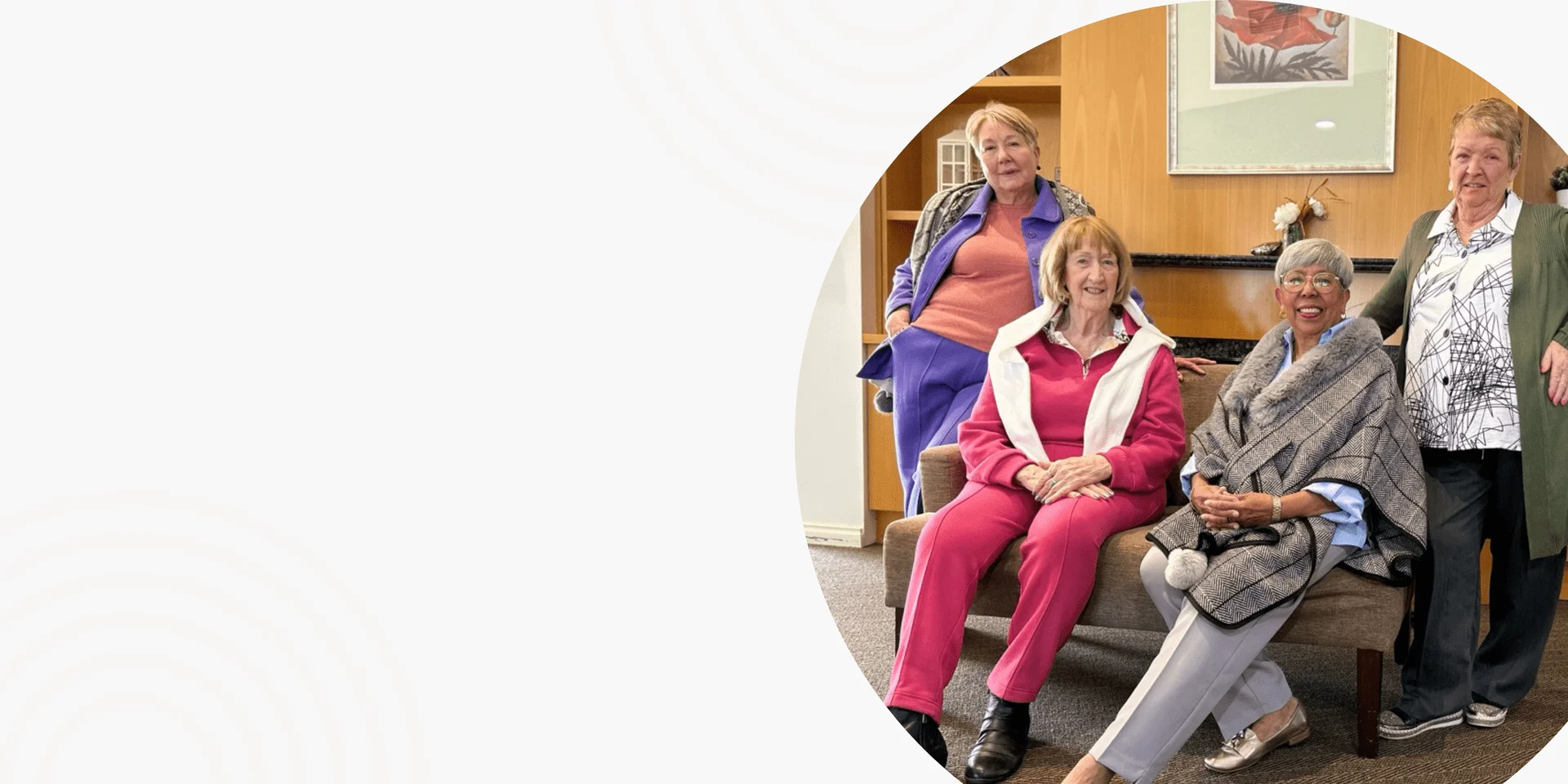 Mature women relaxing in a lounge room, wearing bright everyday outfits including pink trousers and a red jacket
